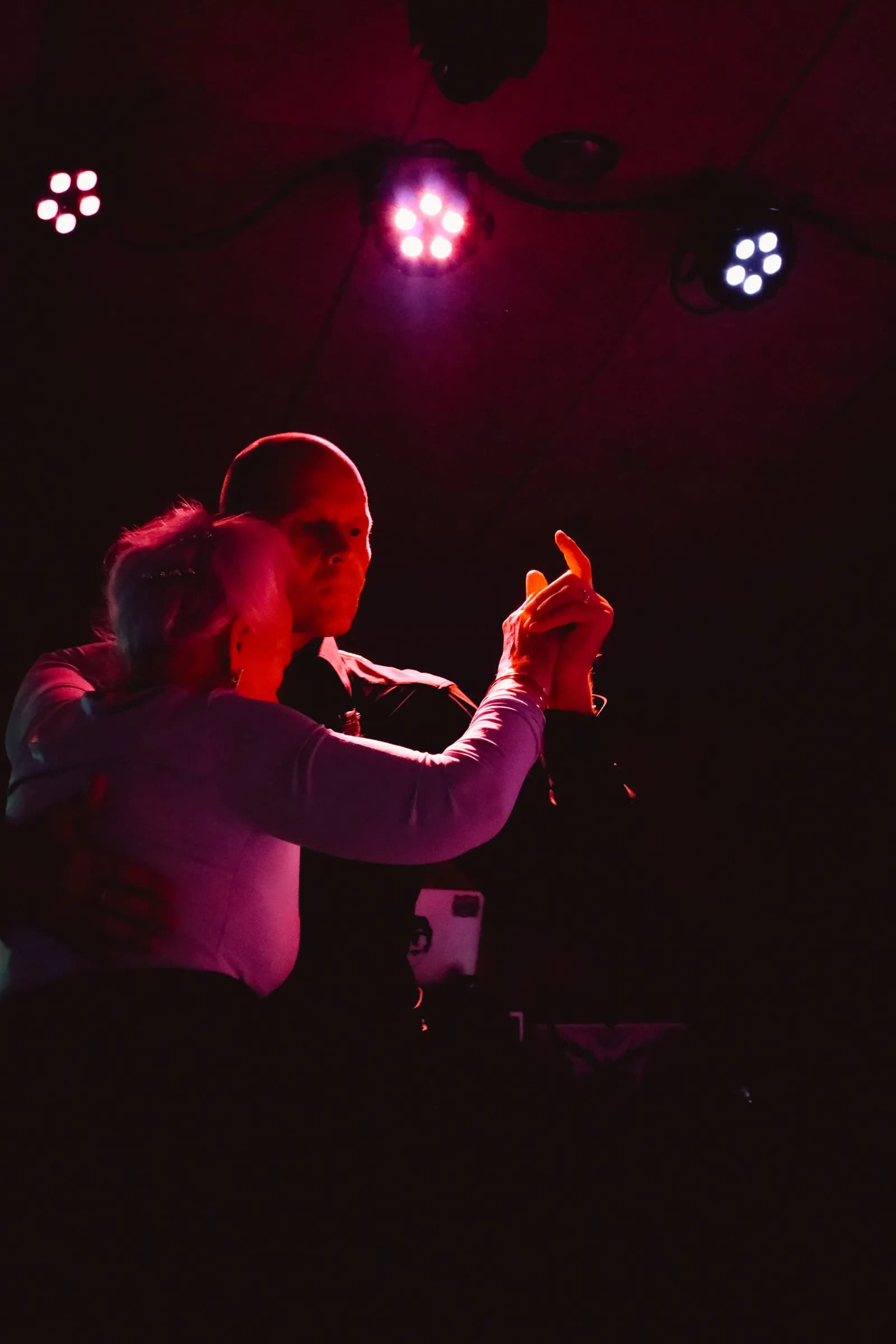 Older couple dancing tango under the red lamps of a milonga