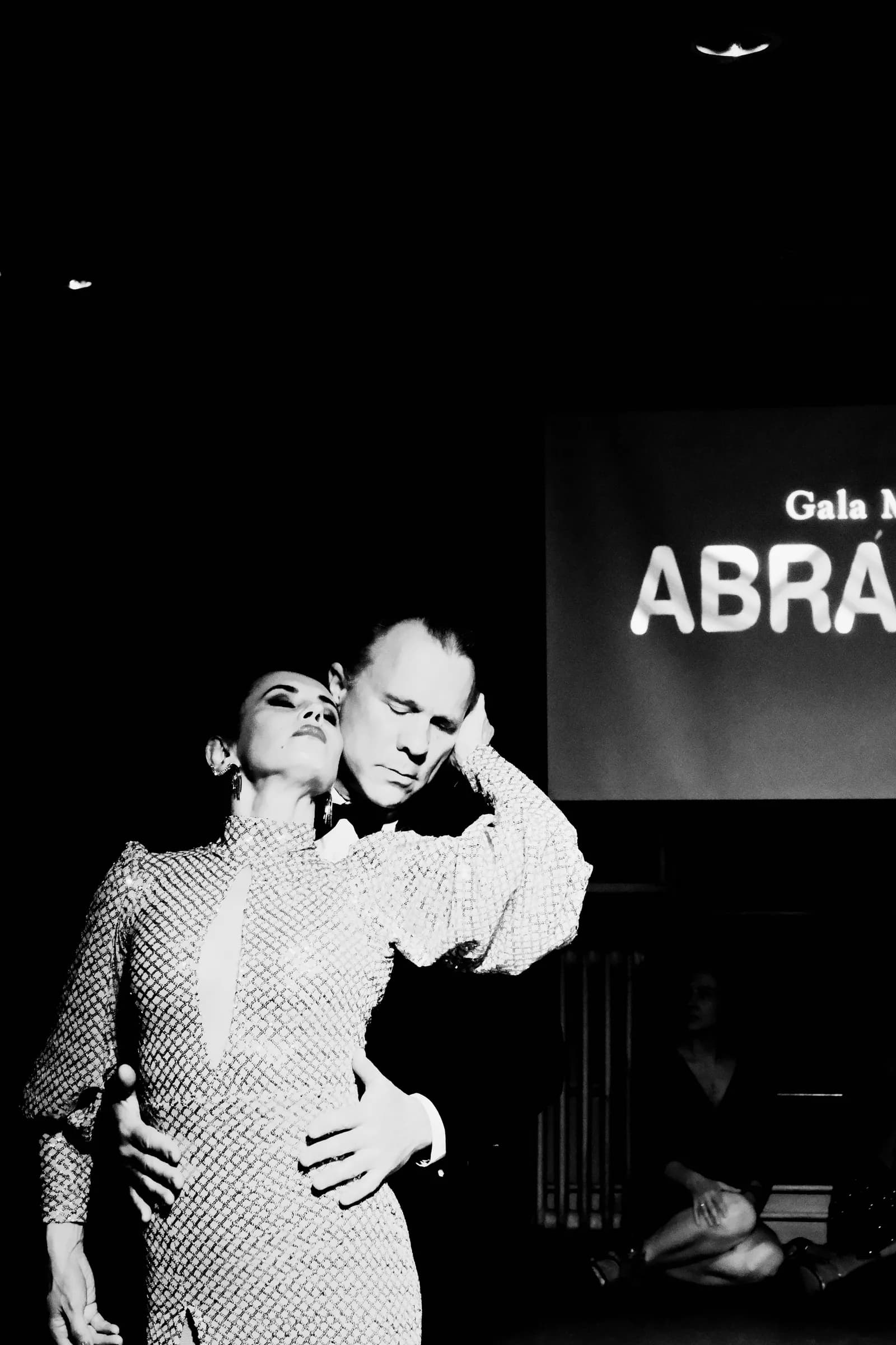 Woman in a sequinned dress resting her head against her partner's cheek mid-performance