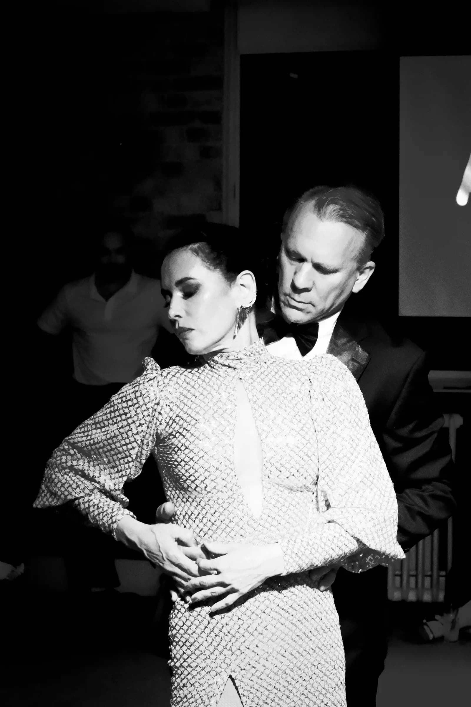 Performing couple in close hold, his hands crossed over hers at her waist