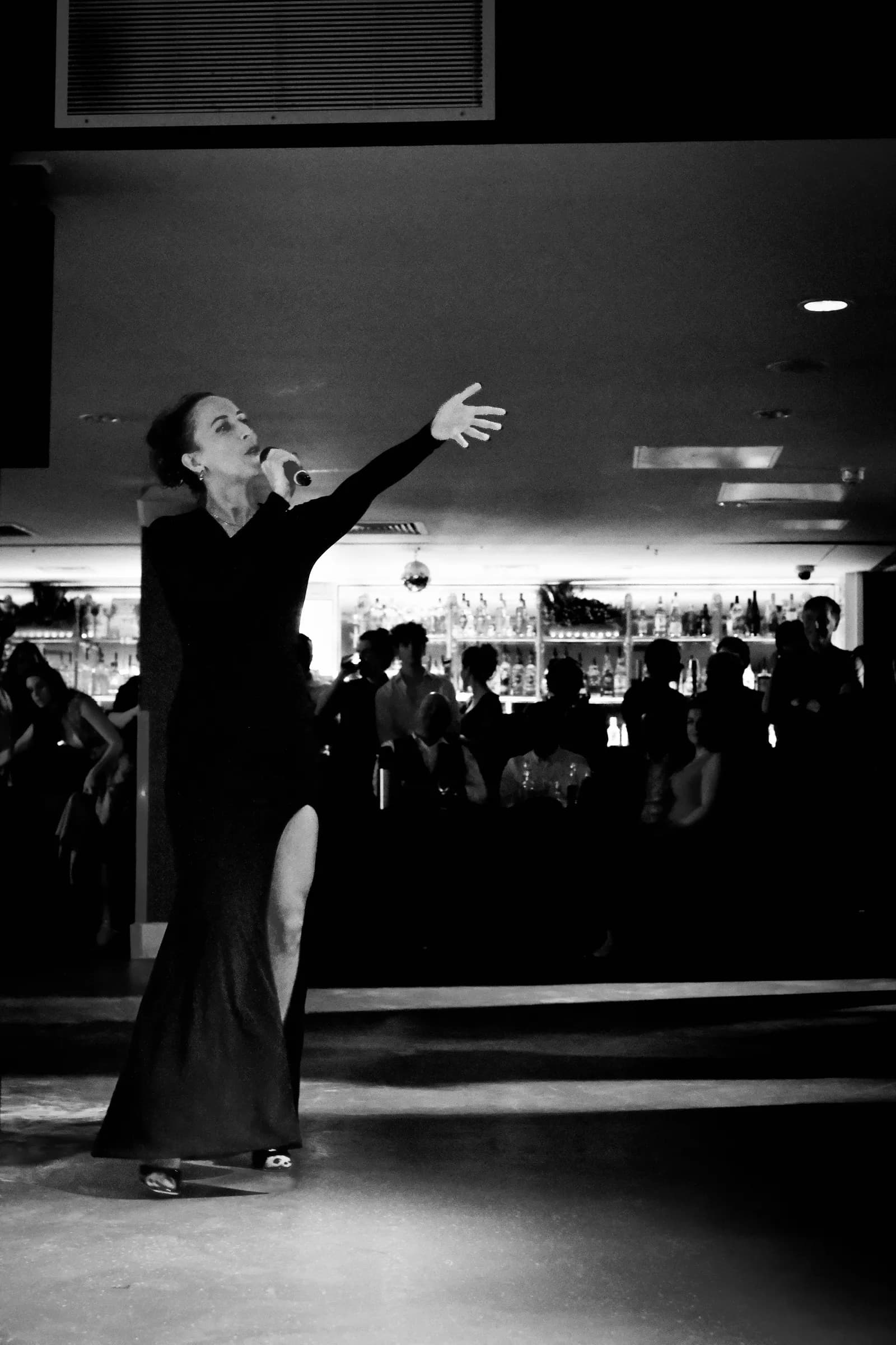 Singer in a long black dress reaching towards the audience across the dance floor