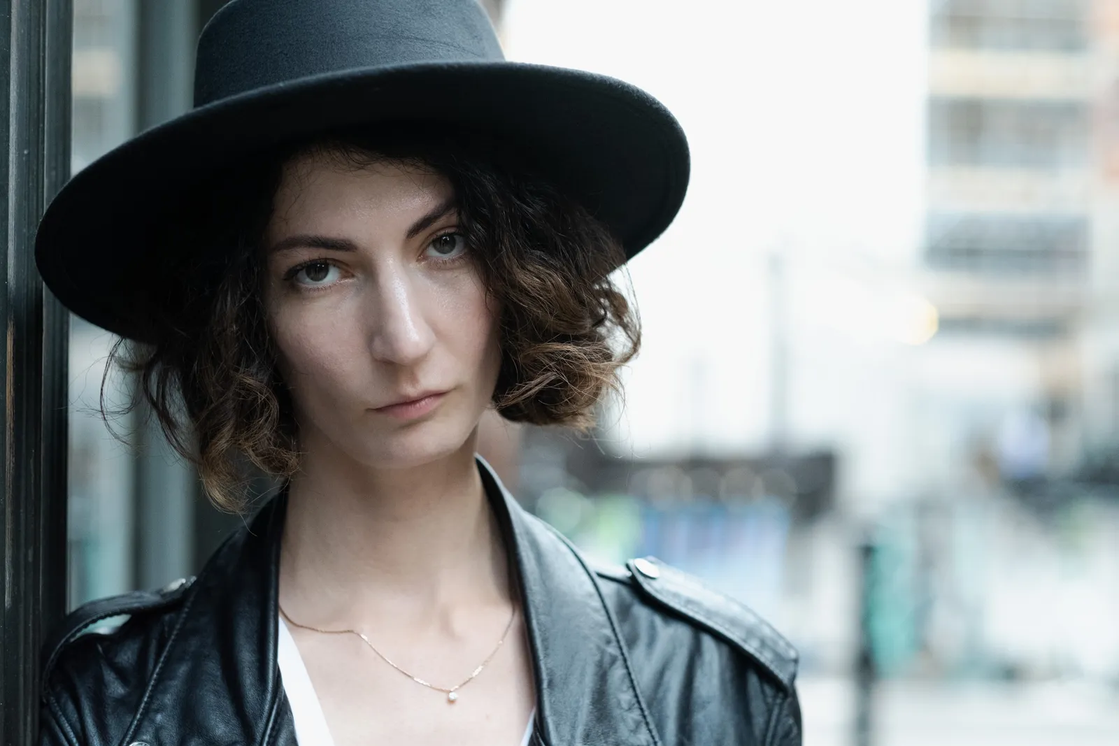 Close portrait of a musician in a wide black hat and leather jacket, looking level into the lens