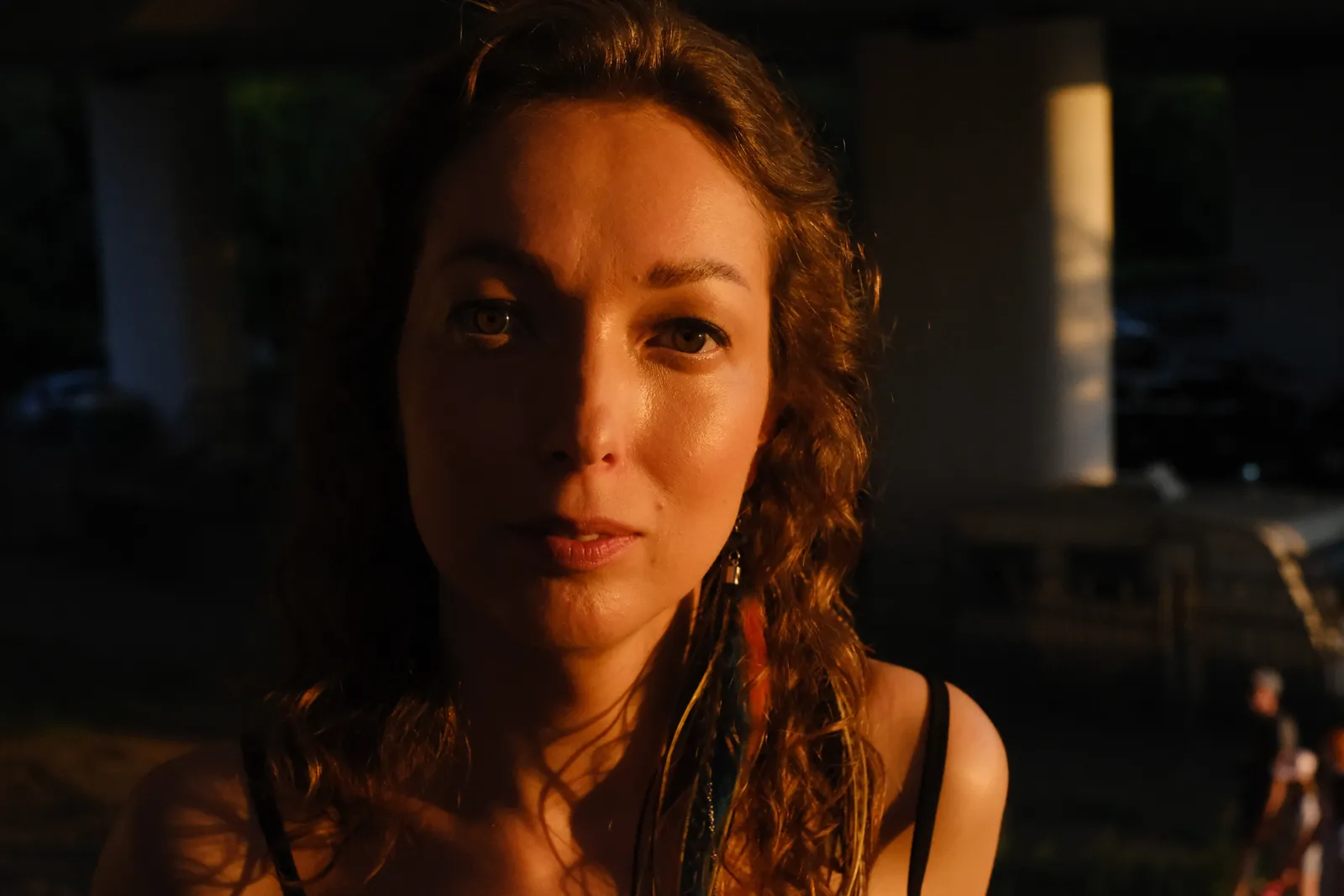 Very close portrait at sunset, feathered earrings, eyes straight into the lens