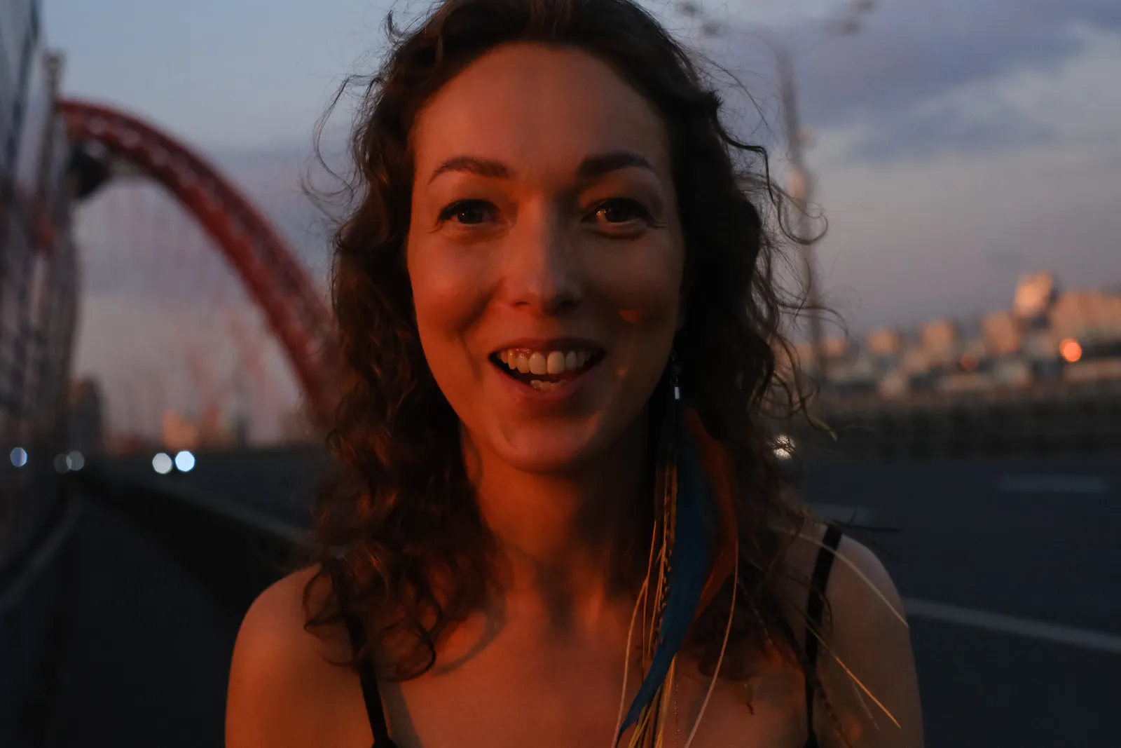 Close portrait of a laughing woman on the bridge at dusk, city lights coming on