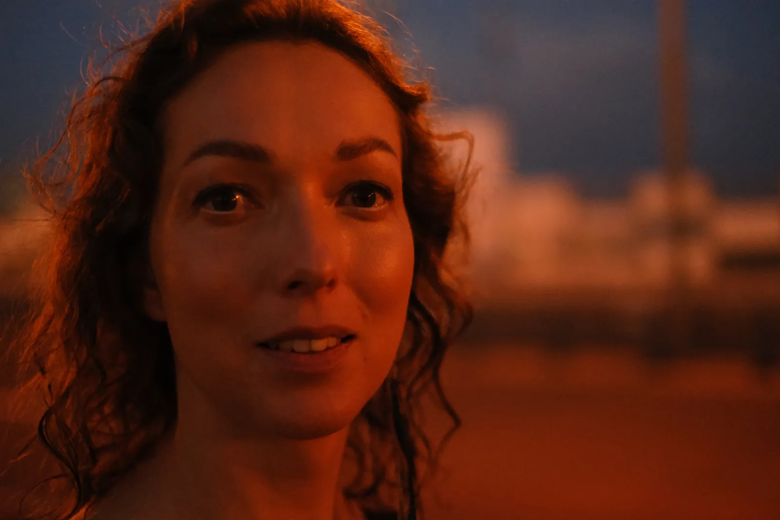 Close portrait under sodium streetlight, wet curls, eyes wide