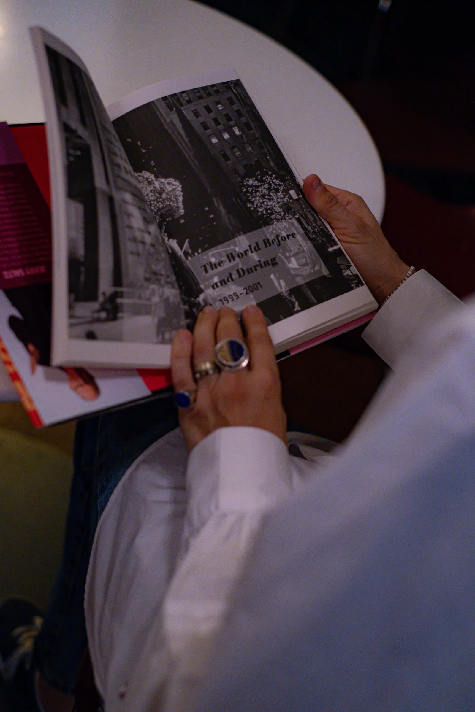 Hands with lacquered nails turning the pages of a photography book on a white table