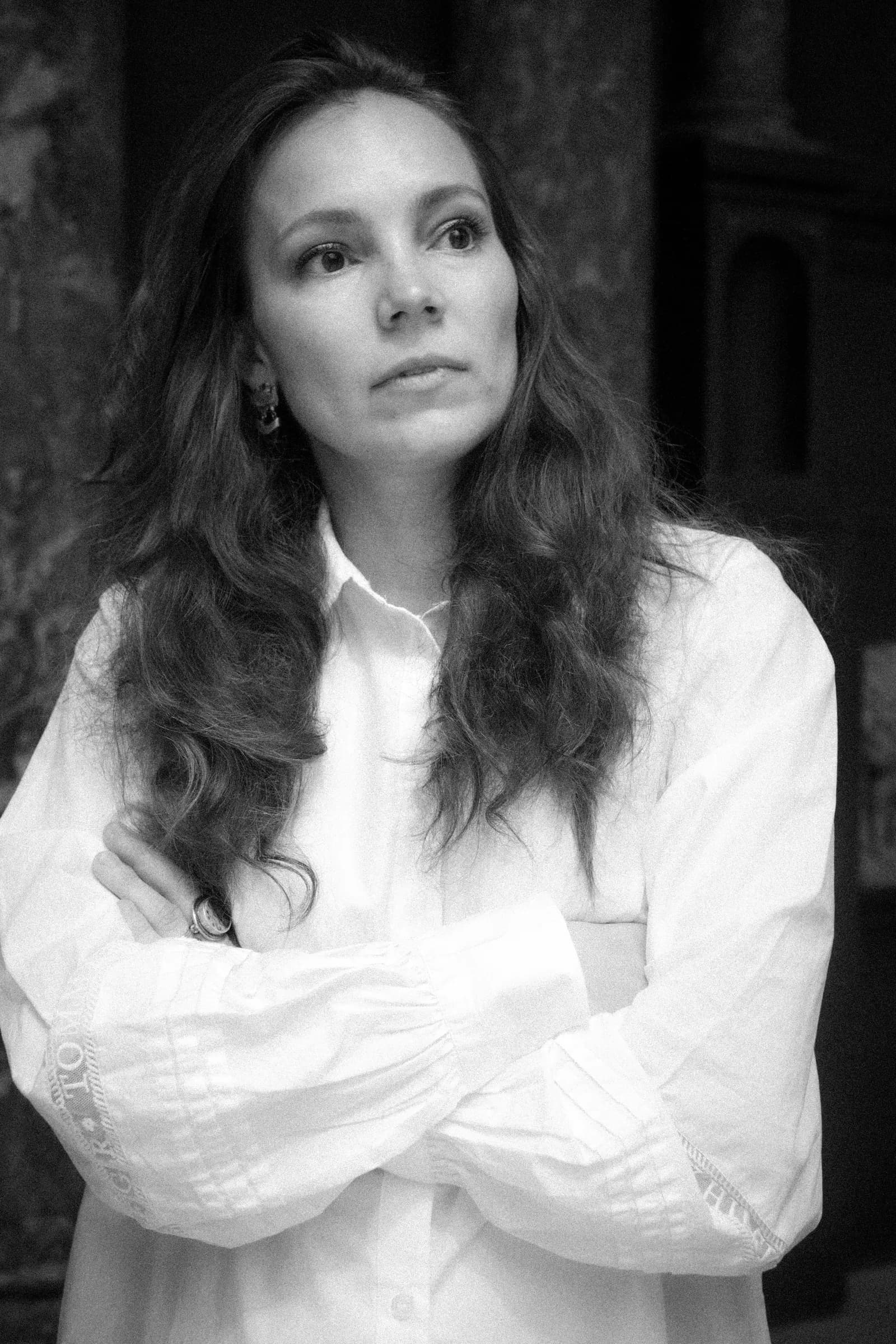 Black and white portrait of a long-haired woman in a white shirt, arms crossed