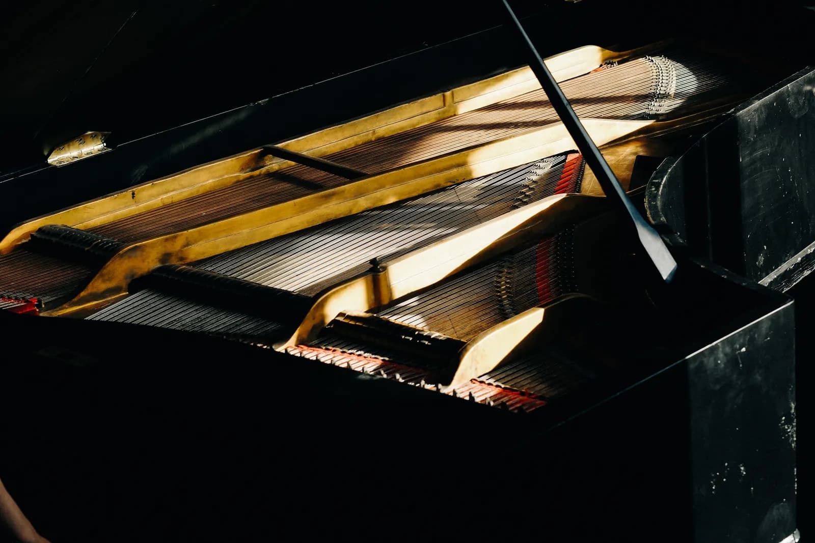 Open grand piano lid over glowing hammers and strings in the dark
