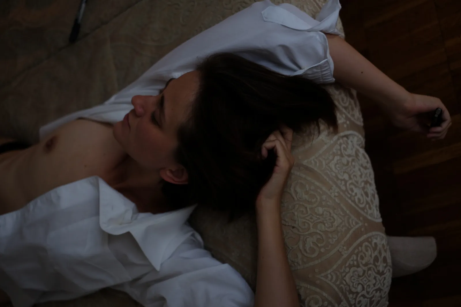 Woman lying back across lace bedding, eyes closed, one hand in her hair