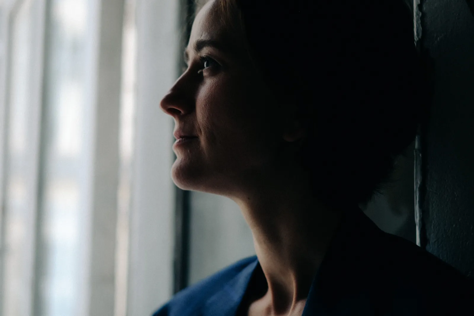 Profile of a woman at a barred window, half her face in shadow